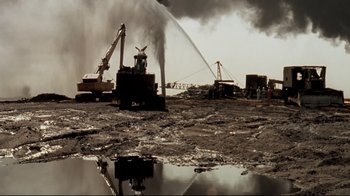 Movie still from “Lessons of Darkness” (1992), directed by Werner Herzog – A dump truck is being used to dump water into the ground; Extreme Wide shot, High angle
