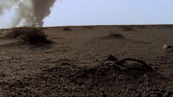 Movie still from “Lessons of Darkness” (1992), directed by Werner Herzog – A dirt field that has a lot of dirt on it; Extreme Wide shot, Low angle