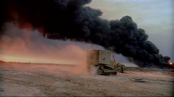 Movie still from “Lessons of Darkness” (1992), directed by Werner Herzog – A tractor is driving down a dusty road; Extreme Wide shot, Low angle