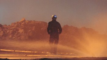 Movie still from “Lessons of Darkness” (1992), directed by Werner Herzog – A person standing in front of a fire hydrant; Wide shot, Low angle