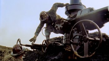 Movie still from “Lessons of Darkness” (1992), directed by Werner Herzog – A man climbing on the side of an old train; Medium shot, Low angle