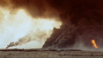 Movie still from “Lessons of Darkness” (1992), directed by Werner Herzog – Smoke billows from a fire in the desert; Extreme Wide shot, Low angle