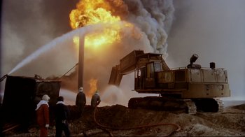 Movie still from “Lessons of Darkness” (1992), directed by Werner Herzog – Three men are standing in front of a large machine; Extreme Wide shot, Low angle