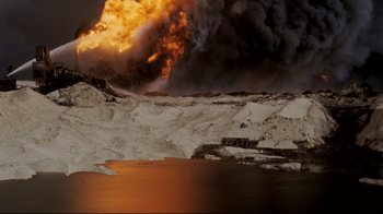 Movie still from “Lessons of Darkness” (1992), directed by Werner Herzog – An oil fire is burning in the distance; Extreme Wide shot, High angle