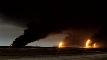 Movie still from “Lessons of Darkness” (1992), directed by Werner Herzog – A fire is burning in the distance near a field; Extreme Wide shot, High angle
