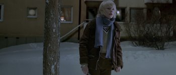 Movie still from “Let the Right One In” (2008), directed by Tomas Alfredson – A woman wearing a brown jacket and a blue scarf; Medium shot, Low angle