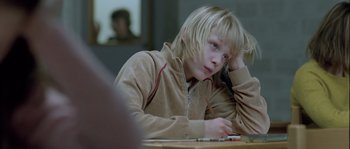 Movie still from “Let the Right One In” (2008), directed by Tomas Alfredson – A young girl sitting at a table with a cell phone in front of her face; Close Up shot, Over the shoulder angle