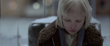 Movie still from “Let the Right One In” (2008), directed by Tomas Alfredson – A young blonde haired woman wearing a brown jacket; Close Up shot, Over the shoulder angle