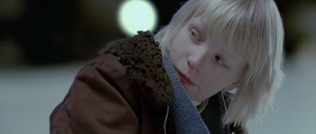 Movie still from “Let the Right One In” (2008), directed by Tomas Alfredson – A young blonde girl wearing a brown jacket; Close Up shot, Over the shoulder angle