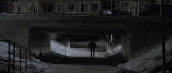Movie still from “Let the Right One In” (2008), directed by Tomas Alfredson – A man walking down a snowy sidewalk at night; Extreme Wide shot, High angle
