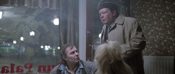 Movie still from “Let the Right One In” (2008), directed by Tomas Alfredson – Two men and a woman are talking in a room; Medium shot, Over the shoulder angle