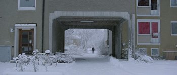 Movie still from “Let the Right One In” (2008), directed by Tomas Alfredson – A person walking down a snowy path under a bridge; Extreme Wide shot, Low angle