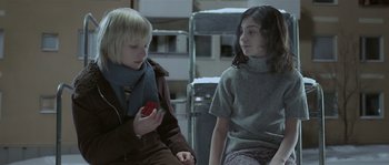Movie still from “Let the Right One In” (2008), directed by Tomas Alfredson – Two young people are sitting together and one is holding a cell phone; Medium shot, High angle