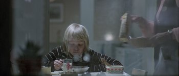 Movie still from “Let the Right One In” (2008), directed by Tomas Alfredson – A young child sitting at a table with a bowl of food; Medium shot, Over the shoulder angle