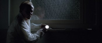 Movie still from “Let the Right One In” (2008), directed by Tomas Alfredson – A man is holding a flashlight in front of a window; Medium shot, Low angle