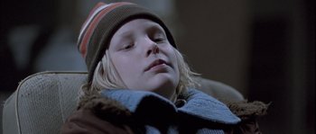 Movie still from “Let the Right One In” (2008), directed by Tomas Alfredson – A young child wearing a winter hat and a sweater; Close Up shot, Low angle