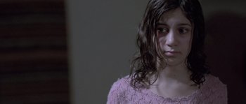 Movie still from “Let the Right One In” (2008), directed by Tomas Alfredson – A young girl in a pink sweater looking at the camera; Close Up shot, Over the shoulder angle
