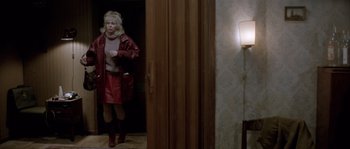 Movie still from “Let the Right One In” (2008), directed by Tomas Alfredson – A woman in a red coat walking through a room; Wide shot, High angle
