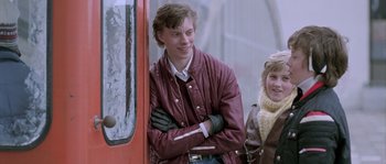 Movie still from “Let the Right One In” (2008), directed by Tomas Alfredson – A young man standing next to a red bus; Medium shot, Over the shoulder angle