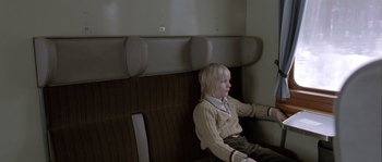 Movie still from “Let the Right One In” (2008), directed by Tomas Alfredson – A person sitting on a bench in a room; Medium shot, High angle