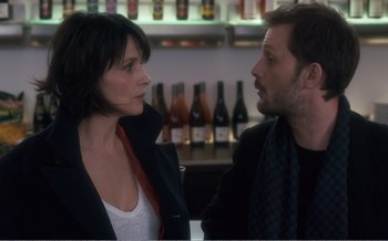 Movie still from “Let the Sunshine In” (2017), directed by Claire Denis – A man and a woman standing next to each other in front of bottles; Close Up shot, Over the shoulder angle