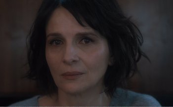 Movie still from “Let the Sunshine In” (2017), directed by Claire Denis – A woman's face in a dark room; Close Up shot, Over the shoulder angle