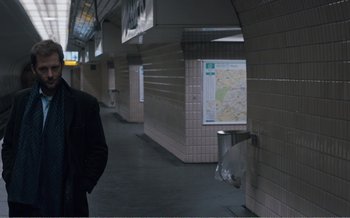 Movie still from “Let the Sunshine In” (2017), directed by Claire Denis – A man standing in front of a map in a subway station; Wide shot, Over the shoulder angle