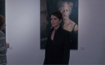 Movie still from “Let the Sunshine In” (2017), directed by Claire Denis – A woman standing in front of a painting of a woman; Medium shot, Over the shoulder angle