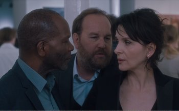 Movie still from “Let the Sunshine In” (2017), directed by Claire Denis – A group of people standing next to each other in a room; Close Up shot, Over the shoulder angle