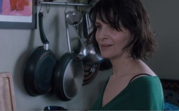 Movie still from “Let the Sunshine In” (2017), directed by Claire Denis – A woman standing in front of pots and pans; Close Up shot, Over the shoulder angle