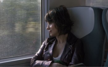 Movie still from “Let the Sunshine In” (2017), directed by Claire Denis – A woman in a leather jacket looking out a window; Close Up shot, High angle