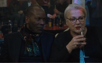 Movie still from “Let the Sunshine In” (2017), directed by Claire Denis – A man and a woman sitting next to each other holding a glass; Close Up shot, Over the shoulder angle
