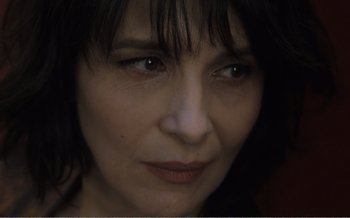 Movie still from “Let the Sunshine In” (2017), directed by Claire Denis – A woman's face in a dimly - lit room; Close Up shot, High angle