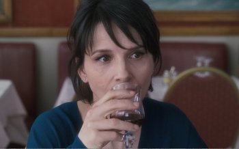 Movie still from “Let the Sunshine In” (2017), directed by Claire Denis – A person holding a glass of wine; Close Up shot, Over the shoulder angle