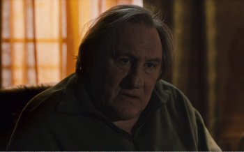 Movie still from “Let the Sunshine In” (2017), directed by Claire Denis – An older man with long gray hair stares at the camera; Close Up shot, Low angle