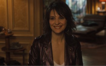 Movie still from “Let the Sunshine In” (2017), directed by Claire Denis – A woman in a leather jacket smiling for the camera; Close Up shot, High angle