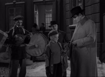 Movie still from “Letter from an Unknown Woman” (1948), directed by Max Ophüls – A group of people standing around a building; Medium shot, Over the shoulder angle