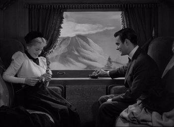 Movie still from “Letter from an Unknown Woman” (1948), directed by Max Ophüls – A man and a woman sitting on a train looking at each other; Medium shot, High angle