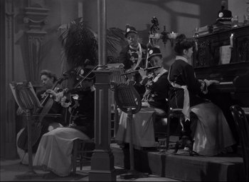 Movie still from “Letter from an Unknown Woman” (1948), directed by Max Ophüls – A black and white photo of a group of people playing instruments; Wide shot, High angle