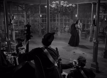 Movie still from “Letter from an Unknown Woman” (1948), directed by Max Ophüls – A black and white photo of a group of people in a room; Wide shot, High angle