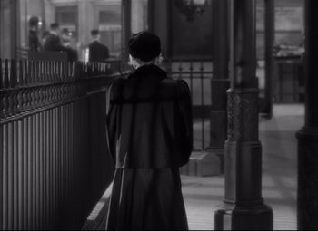 Movie still from “Letter from an Unknown Woman” (1948), directed by Max Ophüls – A man wearing a long coat walking down a street; Medium shot, Over the shoulder angle