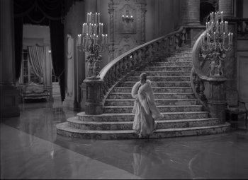 Movie still from “Letter from an Unknown Woman” (1948), directed by Max Ophüls – A woman in a fur coat walking down a set of stairs; Extreme Wide shot, High angle