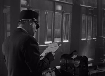 Movie still from “Letter from an Unknown Woman” (1948), directed by Max Ophüls – A man wearing a hat and holding papers; Medium shot, High angle