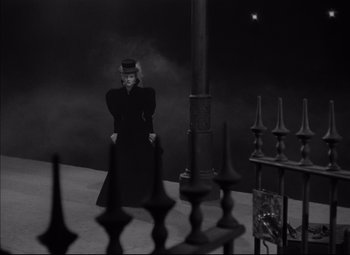 Movie still from “Letter from an Unknown Woman” (1948), directed by Max Ophüls – A woman wearing a top hat and a long black coat; Wide shot, High angle