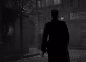 Movie still from “Letter from an Unknown Woman” (1948), directed by Max Ophüls – A man walking down the street at night; Wide shot, Over the shoulder angle