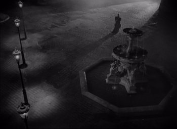 Movie still from “Letter from an Unknown Woman” (1948), directed by Max Ophüls – A black - and - white photo of a fountain in the middle of the night; Extreme Wide shot, High angle
