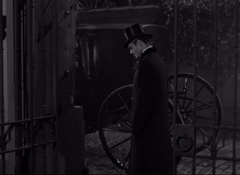 Movie still from “Letter from an Unknown Woman” (1948), directed by Max Ophüls – A man in a top hat standing in front of a carriage; Wide shot, High angle