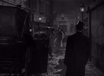 Movie still from “Letter from an Unknown Woman” (1948), directed by Max Ophüls – An old photo of people walking down the street at night; Wide shot, Over the shoulder angle