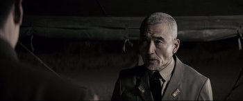 Movie still from “Letters from Iwo Jima” (2006), directed by Clint Eastwood – An older man wearing a suit and tie; Close Up shot, Over the shoulder angle