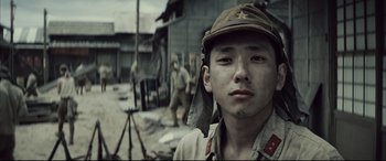 Movie still from “Letters from Iwo Jima” (2006), directed by Clint Eastwood – A young man wearing a hat standing in front of a group of soldiers; Close Up shot, Low angle